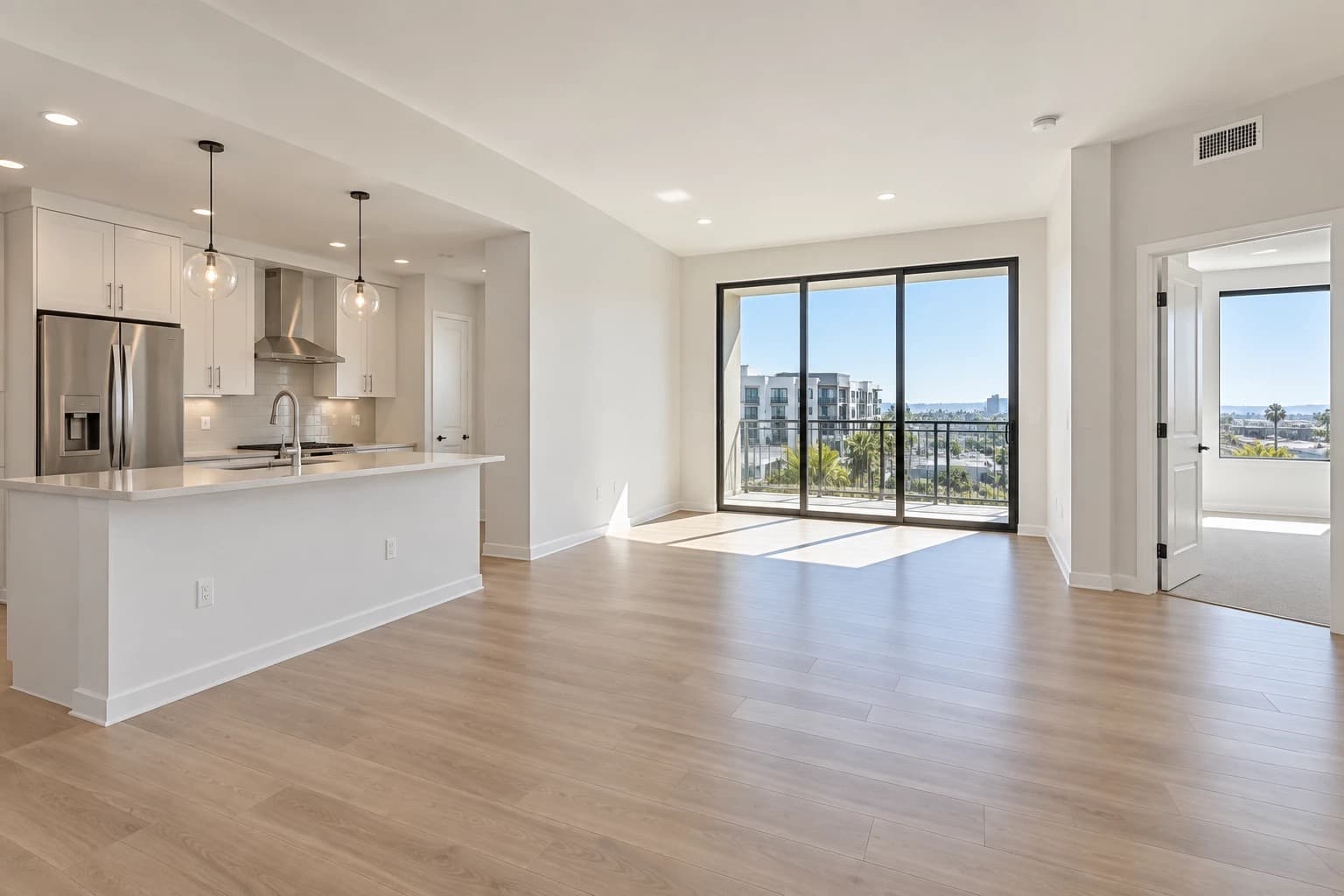 Bright, completely empty apartment with spotless floors, an open kitchen, and a city-view balcony