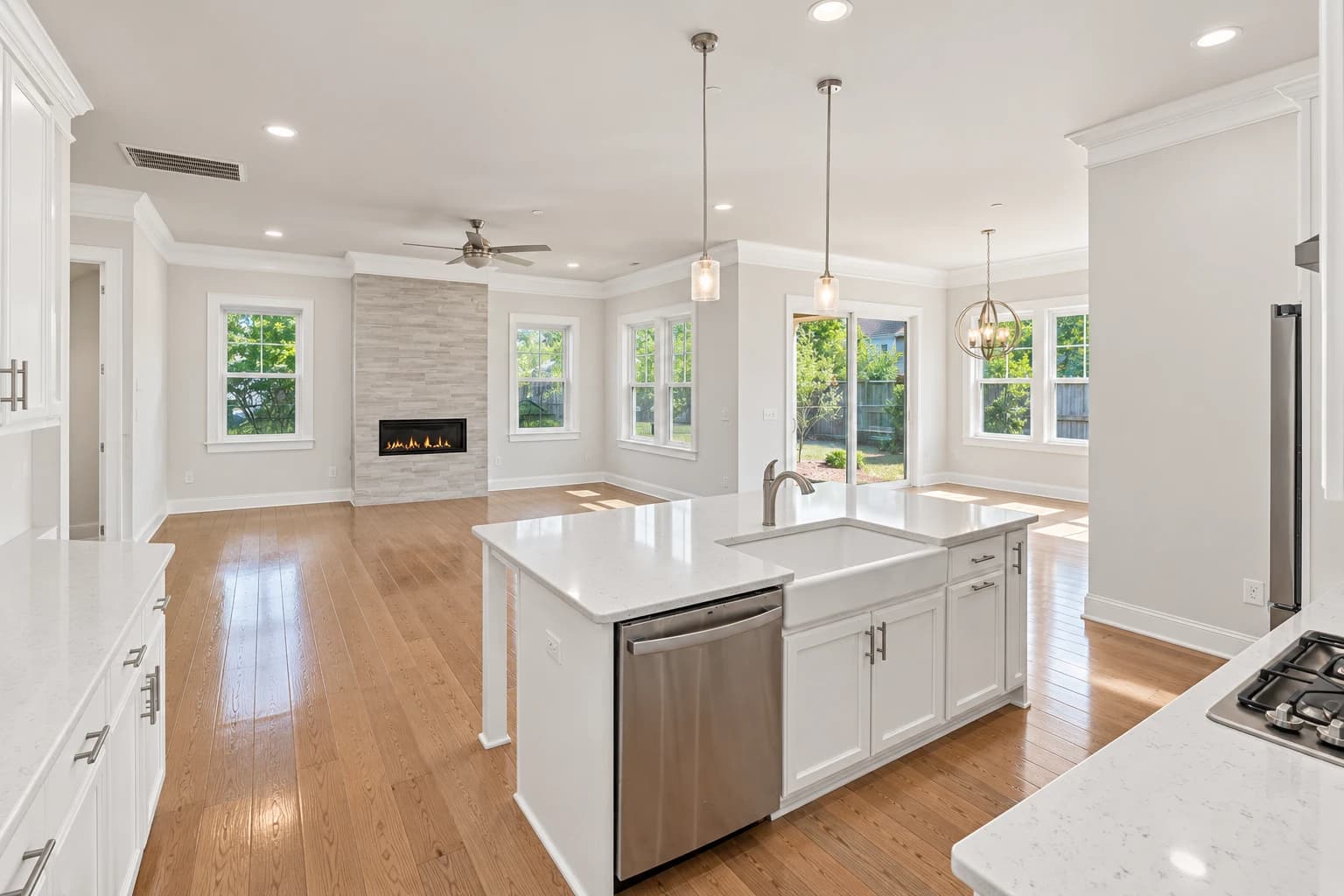 Bright, empty open-concept kitchen and living room with a stone fireplace, ready for its next tenant