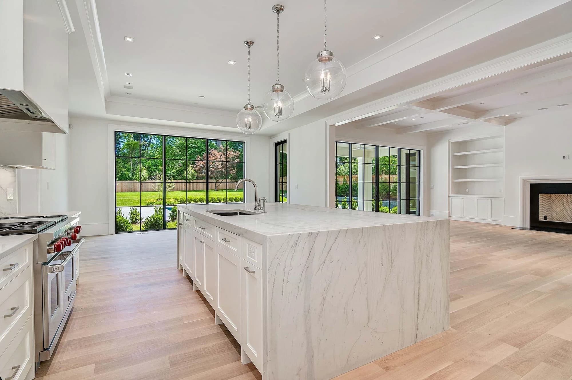 Newly finished luxury kitchen with a marble waterfall island, black steel windows, and an open-concept living area